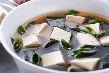 Bowl with miso soup on a gray background.