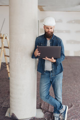 Young builder or architect using a laptop on site