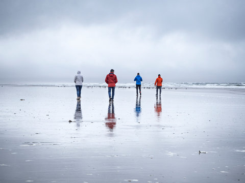 people walking on the beach on a cloudy day