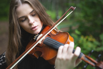 portrait close up of a beautiful girl violinist who lowered his eyes enthusiastically playing the violin romantic work © Denis Ivanov