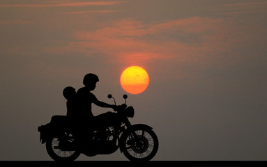 Obraz na płótnie Canvas silhouette fatherand son ride classic motorcycle on sunset