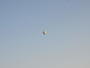 High in the blue sky is a multi-colored balloon.