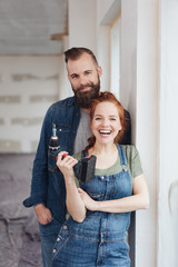 Man standing behind partner while she holds drill
