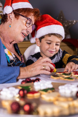 Grandmother and grandson decorating cookies on Christmas time