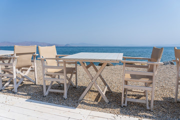 Empty table and chairs in restaurant, Greece. Beach cafe near sea, outdoors. Travel and vacation concept