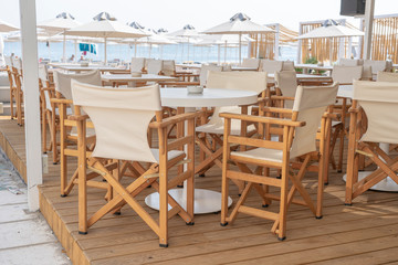 Fototapeta na wymiar Empty table and chairs in restaurant, Greece. Beach cafe near sea, outdoors. Travel and vacation concept