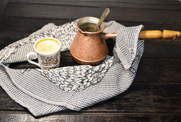 On the table is a copper rod with freshly brewed coffee, a cup.