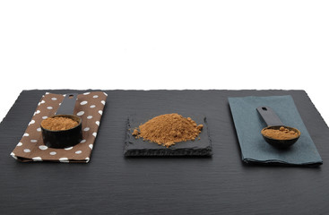 Carob in Messlöffel auf Schiefer