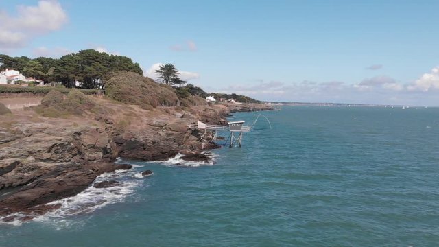 Beautiful drone shot of traditional french fisherman cabin on rocky cliff, blue sky with little clouds and green sea water pornic, france 1-9-19
