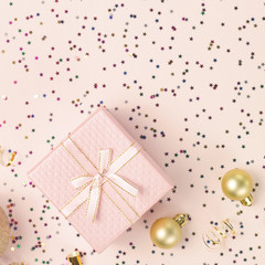 Obraz na płótnie Canvas Gift and Christmas tree toys on pink background with shiny stars