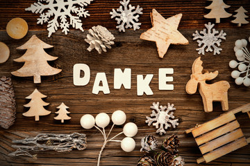 White Letters Building The Word Danke Means Thank You. Wooden Christmas Decoration Like Tree, Sled And Star. Brown Wooden Background