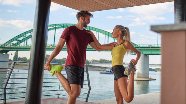 Modern woman and man exercising in urban surroundings near the river.
