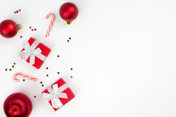 Red Christmas gifts, balls, star confetti, candy canes on white background. Congratulation, Happy New Year concept. Top view, flat lay, copy space