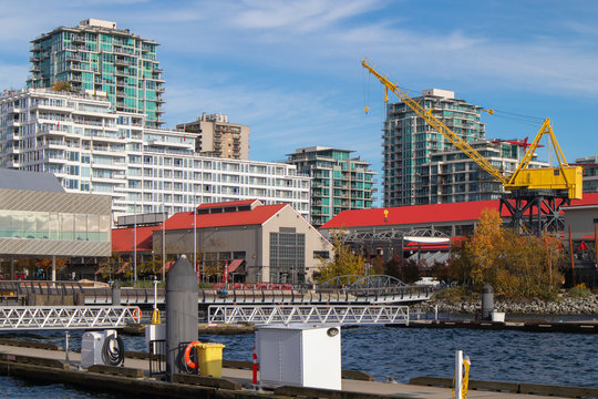 City waterfront. Modern residential apartment buildings with large yellow crane. North Vancouver, (British Columbia, Canada) quay.