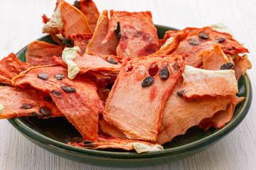 Dried pulp of watermelon lies on a green plate on a white wooden background, side view from above