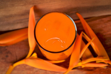 Still Life Glass of Fresh Orange Juice with to yellow flowers.