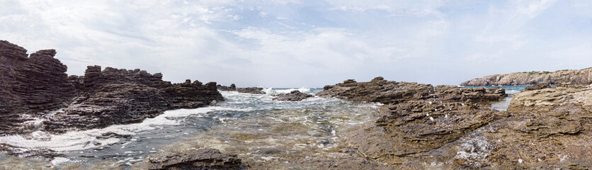 Fototapeta na wymiar The rough seas breaks on the rocks sculpted by the wind forming a wild and suggestive landscape - Immersive 180-degree panoramic view