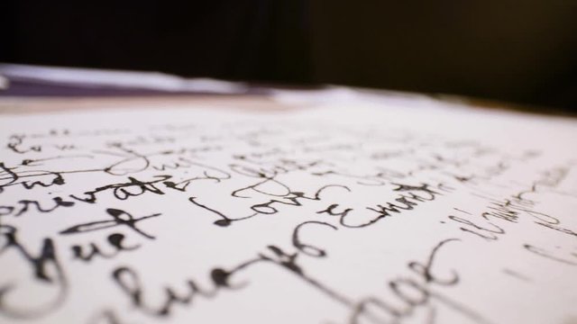 Calligraphy in slow motion. Pan shot of hand written page. Vintage ink pen and quill pen