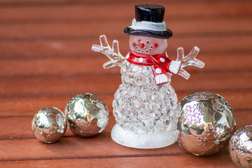 Weihnachtsfigur Schneemann mit rotem Schal und schwarzem Hut begleitet von silbernen Metallkugeln als weihnachtliche Dekoration in der Adventszeit in Zeiten der Vorfreude auf Weihnachten