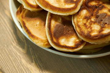 Stack of delicious homemade pancakes on plate, wooden table as background