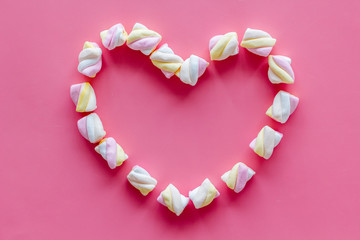 Pastel marshmallows background. Heart shaped set of sweets on pink table top view mockup copy space