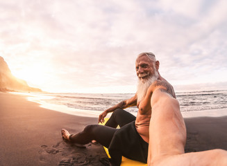 Senior man taking selfie in surfing day - Mature hipster male having fun doing surf at sunset time...