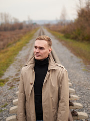 Autumn mood, young guy in a raincoat trench coat underground, street style.