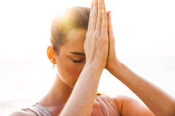 Fitness woman meditate outdoors on beach.