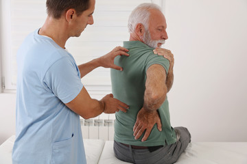 Senior man with back pain. Spine physical therapist and paient. chiropractic pain relief therapy....