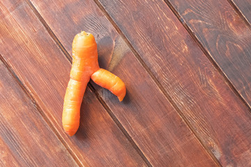 Ugly carrot on woofen table. Food waste reduce concept. Image with copy space, top view