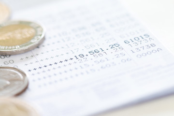 Selective focus of Thai's coins stacked over page of Bank account statement on  white background, Collecting money for investment concept with copy space