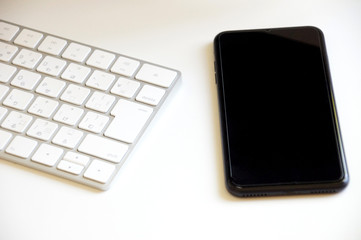 白いキーボードと黒いスマートフォン