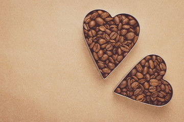 Heap of roasted coffee beans. Two hearts of coffee beans on neutral background. Mockup, layout with text space. Vintage brown parchment. Shape of heart, symbol of love. Kraft paper. Frame, food design