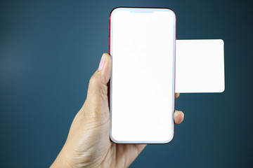 Hand holding a smartphone with white blank screen and holding a blank piece of paper to montage your application isolated.