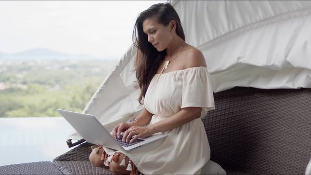 Relaxed woman using laptop on terrace against beautiful landscape