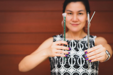Closeup of beautiful asian woman's hands holding a single use plastic straw and reusable stainless straw to show an awareness of reduce plastic waste and contribute to saving environment. No straw.