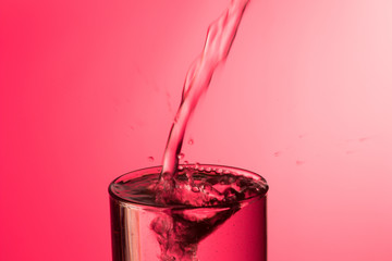 Chorro de agua cayendo sobre un vaso lleno de agua, saltando gotas y chapoteo