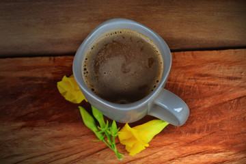 Gray coffee cup Placed on old wooden floors and natural backgrounds with yellow flowers.