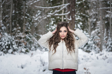 Fototapeta na wymiar Young, beautiful girl, straightens her hair, standing in a snowy forest.