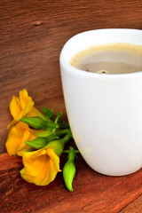 White coffee cup Placed on old wooden floors and natural backgrounds with yellow flowers.