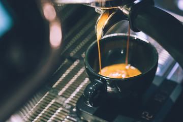 Selective focus picture of a beautiful coffee making machine brewing a shot of espresso into a cup. Coffee culture from around the world, Caffeine Health benefit and risk, Copy space.
