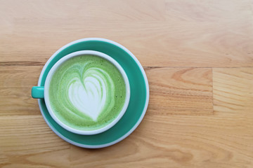 A cup of matcha latte with drawing on the wooden table,