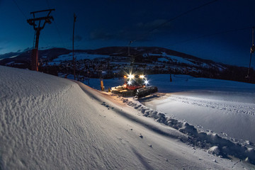 snowcat working on the slope in night