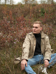 Autumn mood, young guy in a raincoat trench coat underground, street style.