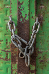 Closed lock with a chain on an old metal door