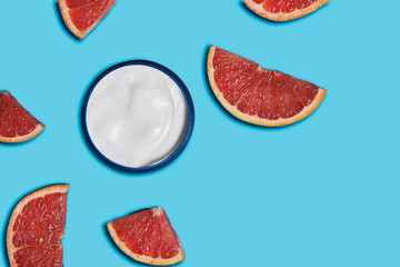 white cream in a jar with grapefruit on blue background. beauty and health care concept. Minimalistic flat lay with copy space. Top view. Cosmetic natural skin care