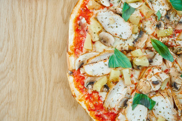 Italian, homemade Hawaiian pizza with chicken and pineapple on a wooden table. Top view food with copy space. Flat lay