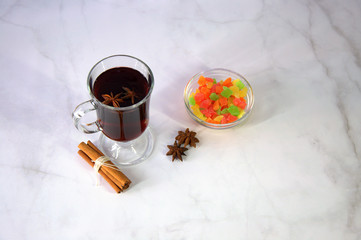 A glass of mulled wine with slices of orange, cinnamon sticks, star anise and dried fruit.