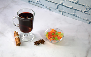 A glass of mulled wine with slices of orange, cinnamon sticks, star anise and dried fruit.