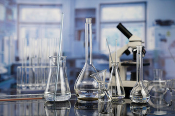 Modern scientific laboratory interior. Laboratory glassware and microscope on the glass table.